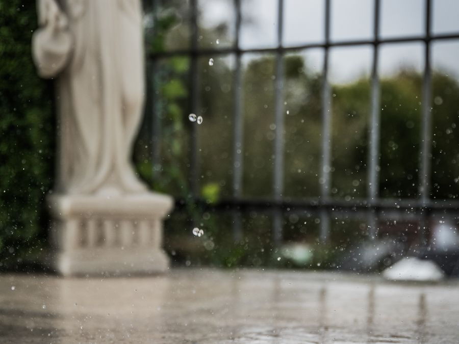 Regentropfen auf einer beschichteten Terrassenfläche vor einer Statue
